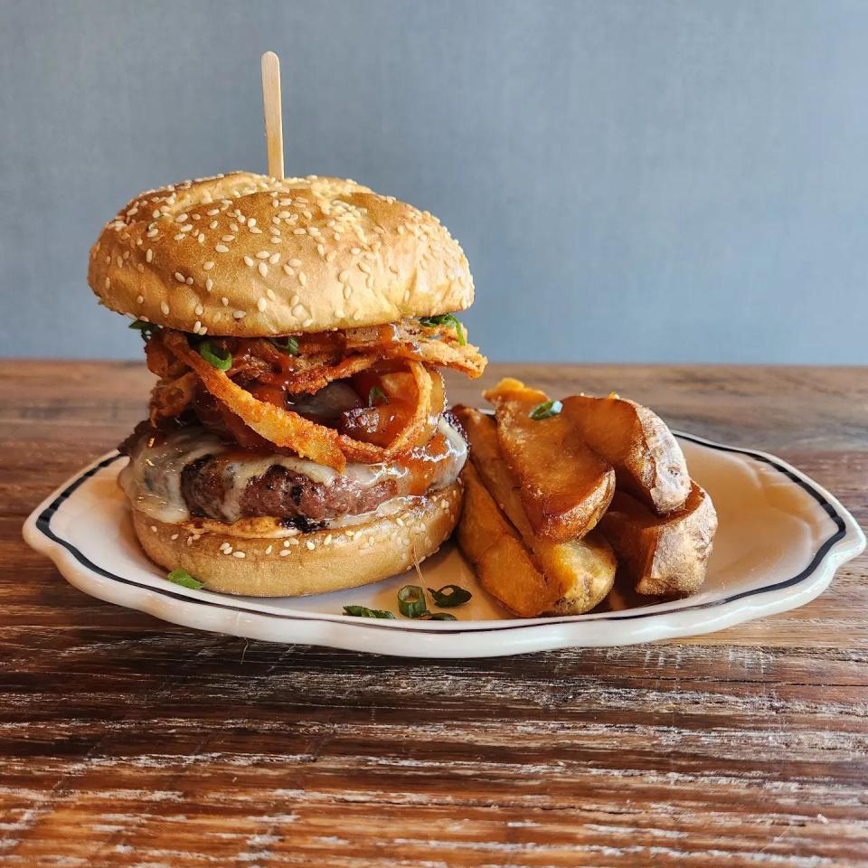 The sawBELLY burger is made with smoked pork belly, ground chuck grind from Tuckaway Tavern, smoked cheddar, applewood bacon, house BBQ sauce, chipotle aioli and mesquite crispy onions.