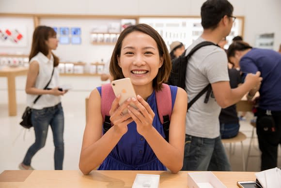 A person holding a gold iPhone 8 inside of an Apple Store.