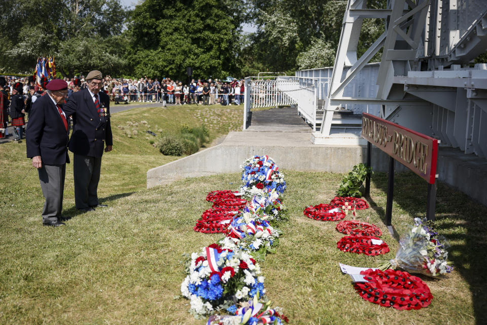 War veterans stand by wreaths of flowers at the Pegasus Bridge, one of the first sites liberated by Allied forces from Nazi Germany, in Benouville, Normandy, Monday June 5, 2023. Dozens of World War II veterans have traveled to Normandy this week to mark the 79th anniversary of D-Day, the decisive but deadly assault that led to the liberation of France and Western Europe from Nazi control. (AP Photo/Thomas Padilla)