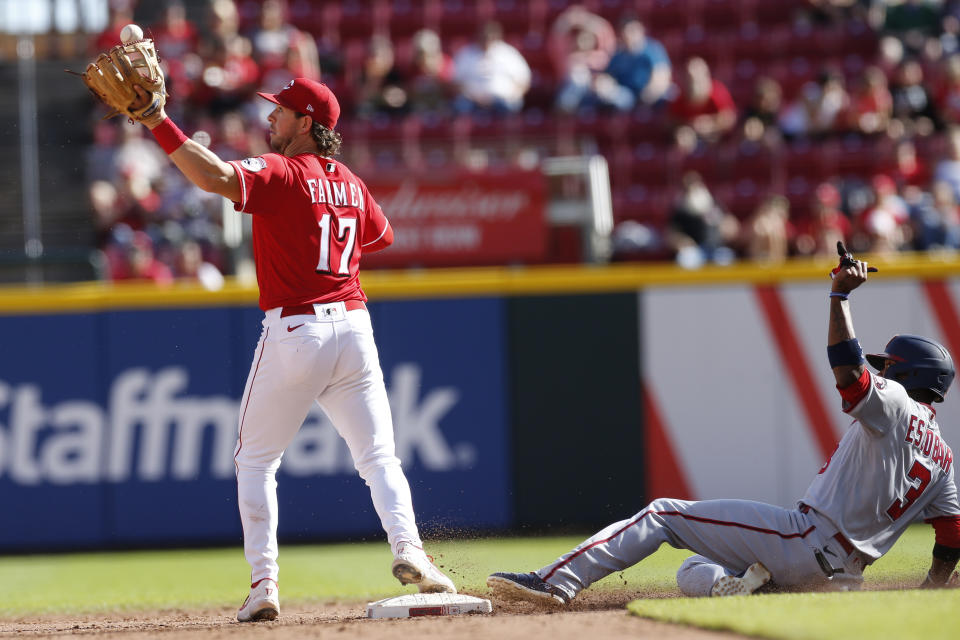 Cincinnati Reds' Kyle Farmer, left, bobbles a ball as Washington Nationals' Alcides Escobar slides into second base during the eighth inning of a baseball game Sunday, Sept. 26, 2021, in Cincinnati. The Reds defeated the Nationals 9-2. (AP Photo/Jay LaPrete)