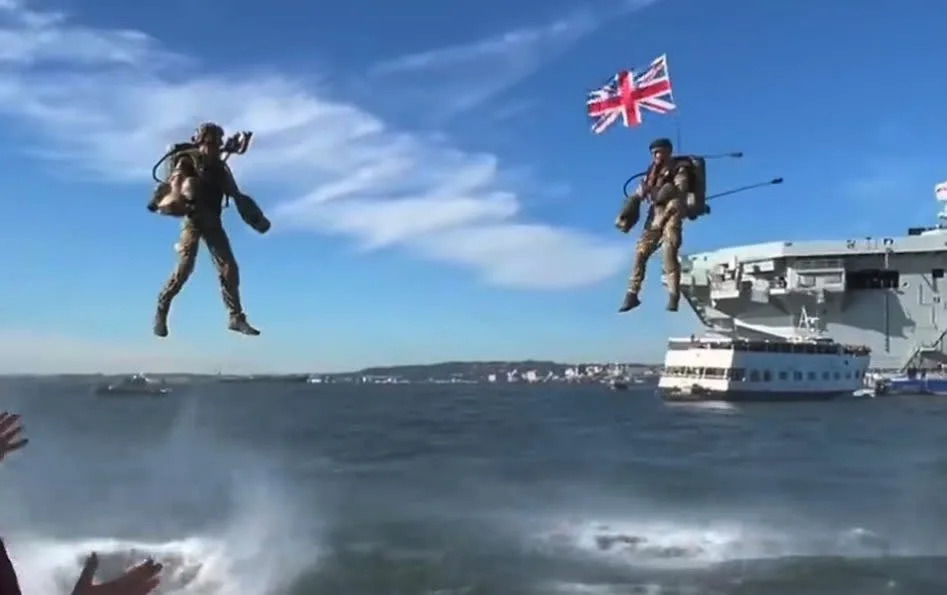 Navy members hovered over the Atlantic Ocean with helmet-steered weapon mounts and tactical suits waving Union Jack flags - You Tube/Gravity Industries