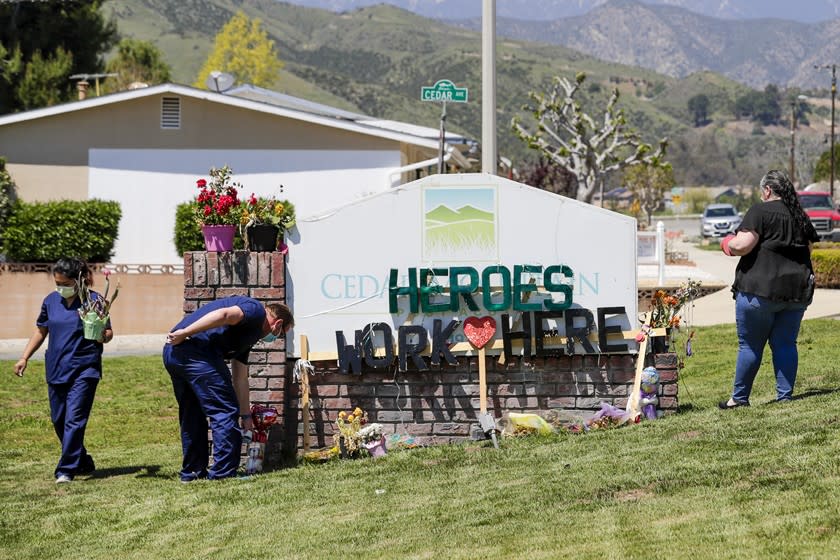 Staff members at Cedar Mountain Post Acute in Yucaipa spruce up a toppled sign that was put up by members of the community to show their support for the nursing staff of the facility.