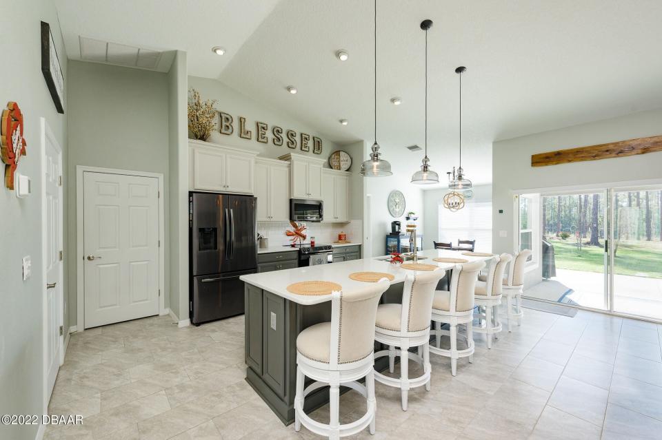 Tile floors cover the huge open-concept living area that joins the upgraded kitchen with a bar and an adjacent eat-in area.