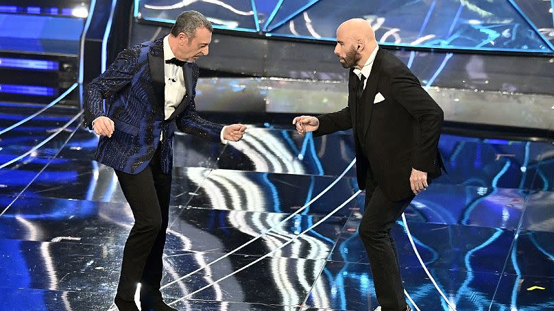 John Travolta, right, and Amadeus perform during the 74th edition of the Sanremo Italian Song Festival at the Ariston Theatre in Sanremo, northern Italy, Tuesday, Feb. 7, 2024