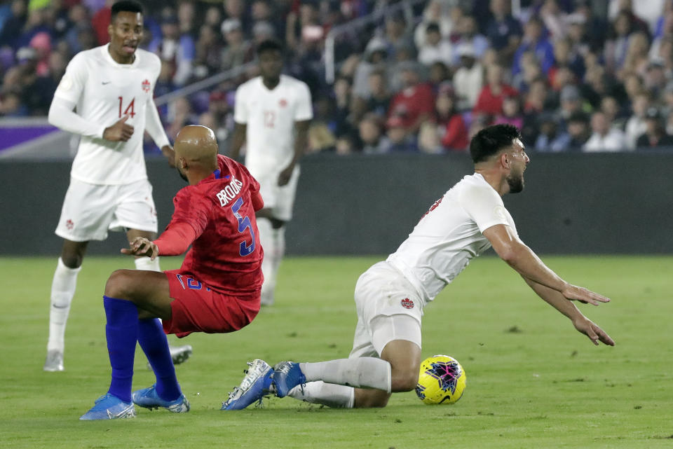 United States midfielder John Brooks (5) and Canada forward Lucas Cavallini, right, fall after they collided while going for the ball during the first half of a CONCACAF Nations League soccer match Friday, Nov. 15, 2019, in Orlando, Fla. (AP Photo/John Raoux)