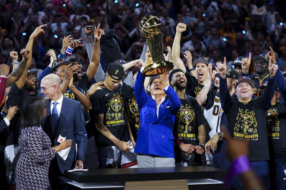 Denver Nuggets owner Stan Kroenke, center, holds up the Larry O'Brien NBA Championship Trophy after the team's victory over the Miami Heat in Game 5 of basketball's NBA Finals, Monday, June 12, 2023, in Denver. (AP Photo/Jack Dempsey)