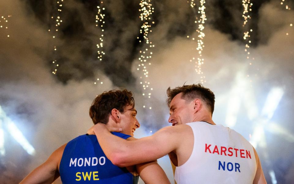 Armand Duplantis and Karsten Warholm hug after their race with smoke and fireworks in the background