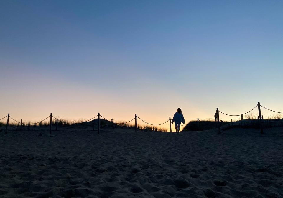 A woman leaves the beach at Fenwick Island State Park as the sun sets,Saturday, Sept. 2, 2023 during the unofficial end to summer, Labor Day Weekend.