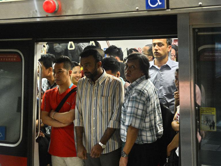 Commuters stands at the doorway of a crowded train on the Singapore subway on February 13, 2013