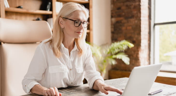 A woman reviews her retirement accounts on her laptop.