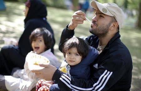 Migrants from Afghanistan eat as they wait to register at a compound outside the Berlin Office of Health and Social Affairs (LaGeSo) in Berlin, Germany September 7, 2015. REUTERS/Fabrizio Bensch