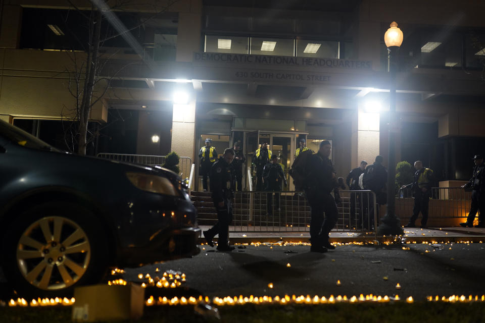 Candles lit by protesters line the street as U.S. Capitol Police officers stand outside the headquarters of the Democratic National Committee Wednesday, Nov. 15, 2023, in Washington. (AP Photo/Nathan Howard)