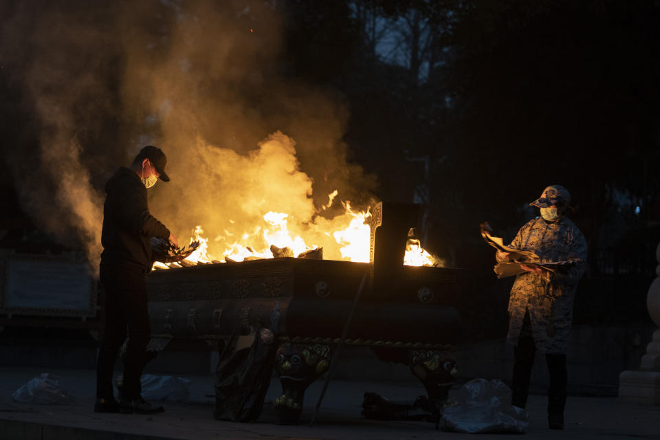 Residents burn paper offerings to a relative who died from the coronavirus on the eve of the anniversary of the 76-day lockdown in the central Chinese city where the coronavirus was first detected in Wuhan in central China's Hubei province, Friday, Jan. 22, 2021. (AP Photo/Ng Han Guan)