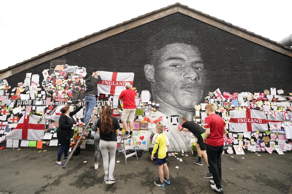 People put up flags and messages on the mural of Manchester United striker and England player Marcus Rashford on the wall of the Coffee House Cafe on Copson Street, Withington, after it had been defaced (PA Wire)