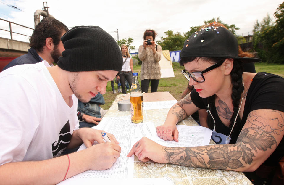 BERLIN, GERMANY - JULY 21: An attendee (R) signs up to compete at the second annual Hipster Olympics on July 21, 2012 in Berlin, Germany. With events such as the "Horn-Rimmed Glasses Throw," "Skinny Jeans Tug-O-War," "Vinyl Record Spinning Contest" and "Cloth Tote Sack Race," the Hipster Olympics both mocks and celebrates the Hipster subculture, which some critics claim could never be accurately defined and others that it never existed in the first place. The imprecise nature of determining what makes one a member means that the symptomatic elements of adherants to the group vary in each country, but the archetype of the version in Berlin, one of the more popular locations for those following its lifestyle, along with London and Brooklyn, includes a penchant for canvas tote bags, the carbonated yerba mate drink Club Mate, analogue film cameras, asymetrical haircuts, 80s neon fashion, and, allegedly, a heavy dose of irony. To some in Berlin, members of the hipster "movement" have replaced a former unwanted identity in gentrifying neighborhoods, the Yuppie, for targets of criticism, as landlords raise rents in the areas to which they relocate, particularly the up-and-coming neighborhood of Neukoelln. (Photo by Adam Berry/Getty Images)