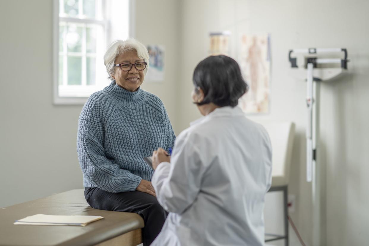 A woman smiles in conversation with her doctor during her appointment.