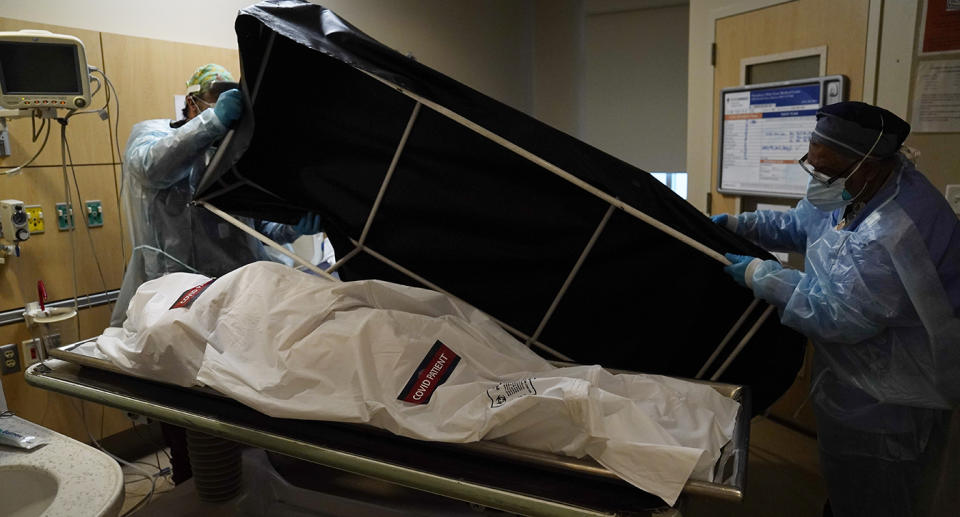 Medical staff put the body of a dead Covid patient into a black container.