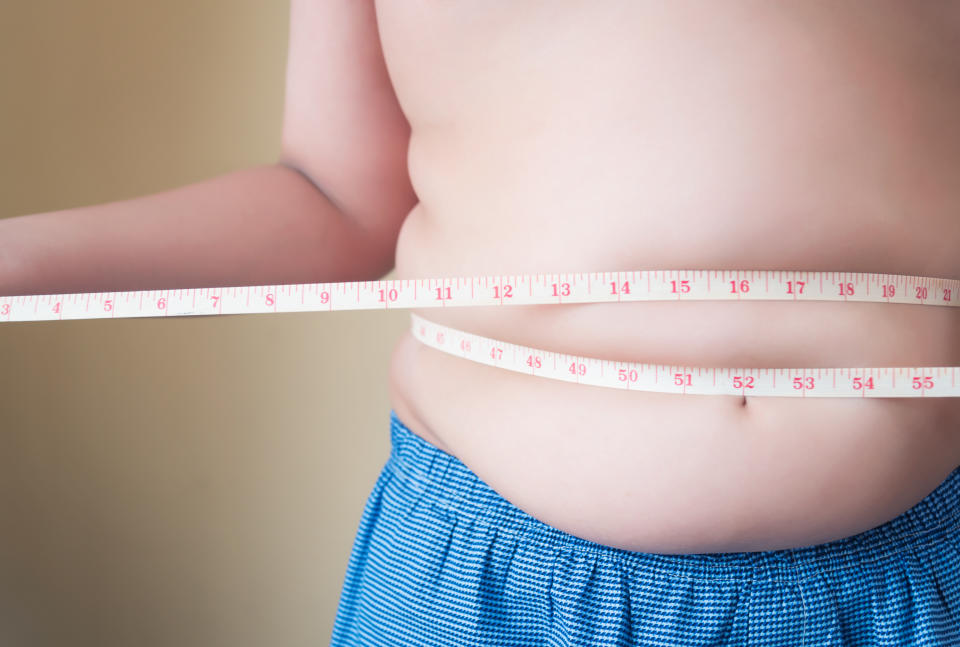 Fat boy with overweight checking out his weight isolated on white background