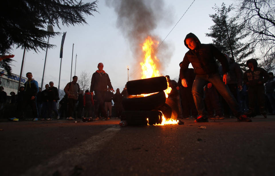 Bosnian protesters gather around a road blockade during protest in Bosnian town of Tuzla, 140 kms north of Sarajevo, on Thursday, Feb. 6. 2014. Violent protests by some thousands of unpaid workers in a northern Bosnian city spread to other parts of the country Thursday and have morphed into widespread discontent about unemployment and alleged rampant corruption, in an election year. Police used tear gas to temporarily disperse the protesters in Tuzla who threw stones at a local government building, then the protesters returned after the tear gas volley, surrounded the empty government building and set tyres and trash on fire.(AP Photo/Amel Emric)