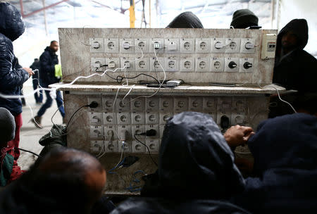 Migrants charge their phones in a migrant camp in Bihac, Bosnia and Herzegovina, December 14, 2018. REUTERS/Antonio Bronic