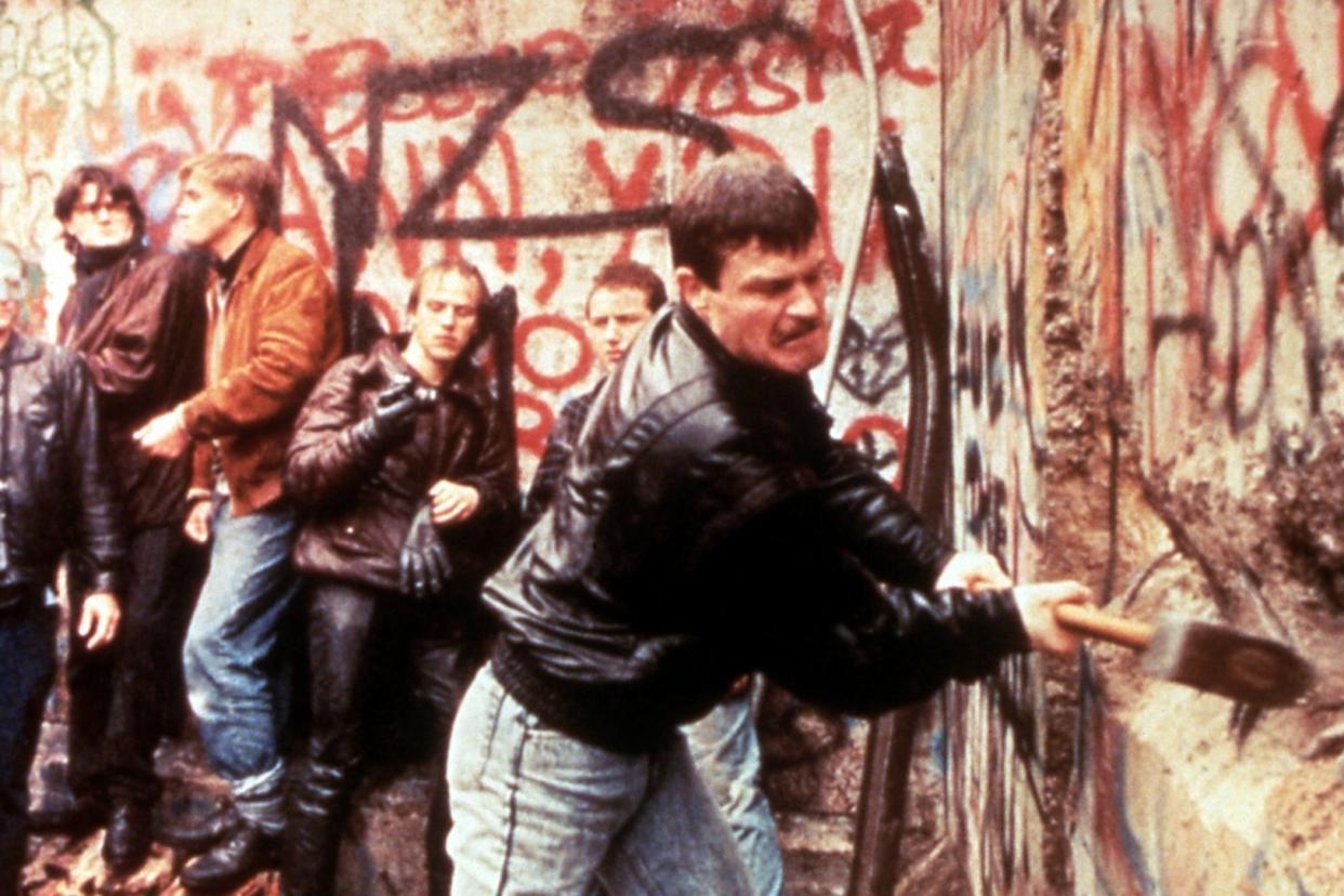 East German guards look on as the Berlin Wall is destroyed in 1989: Alamy