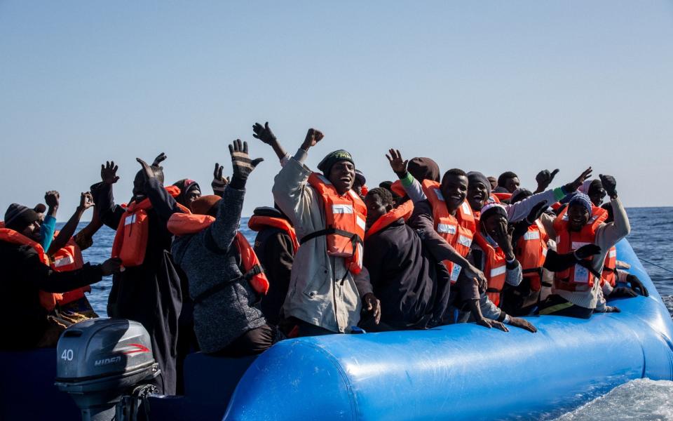 Migrants attempting to cross the Mediterranean celebrate after learning that a boat from a Dutch charity, Sea Watch, will rescue them - AFP