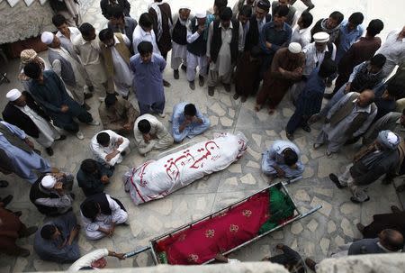 Shi'ite Muslim men from the ethnic Hazara minority mourn beside the coffins of their relatives who were killed after gunmen opened fire on a bus during a funeral ceremony in Quetta October 23, 2014. REUTERS/Naseer Ahmed