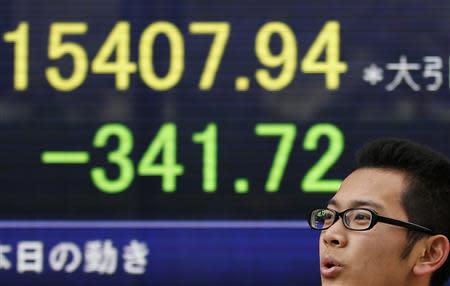 A man stands in front of a stock quotation board displaying Japan's Nikkei average, outside a brokerage in Tokyo December 4, 2013. REUTERS/Toru Hanai