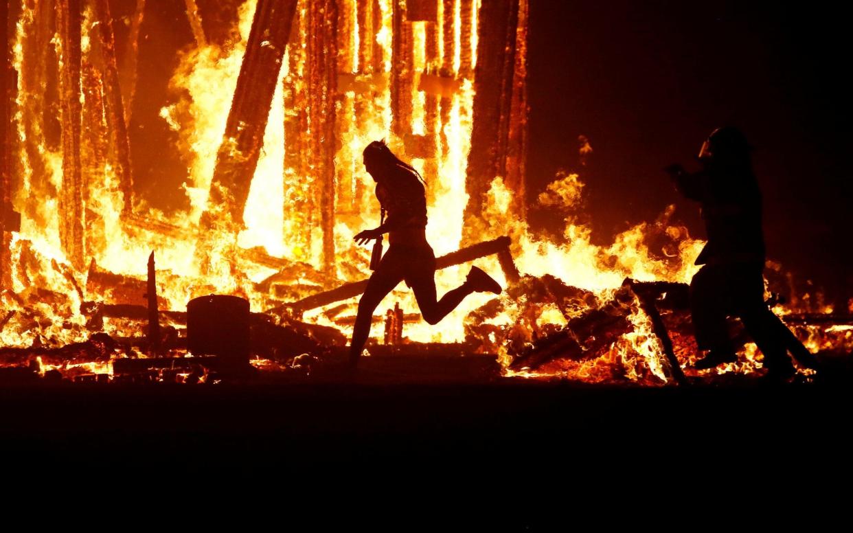 Burning Man participant runs towards the flames of the