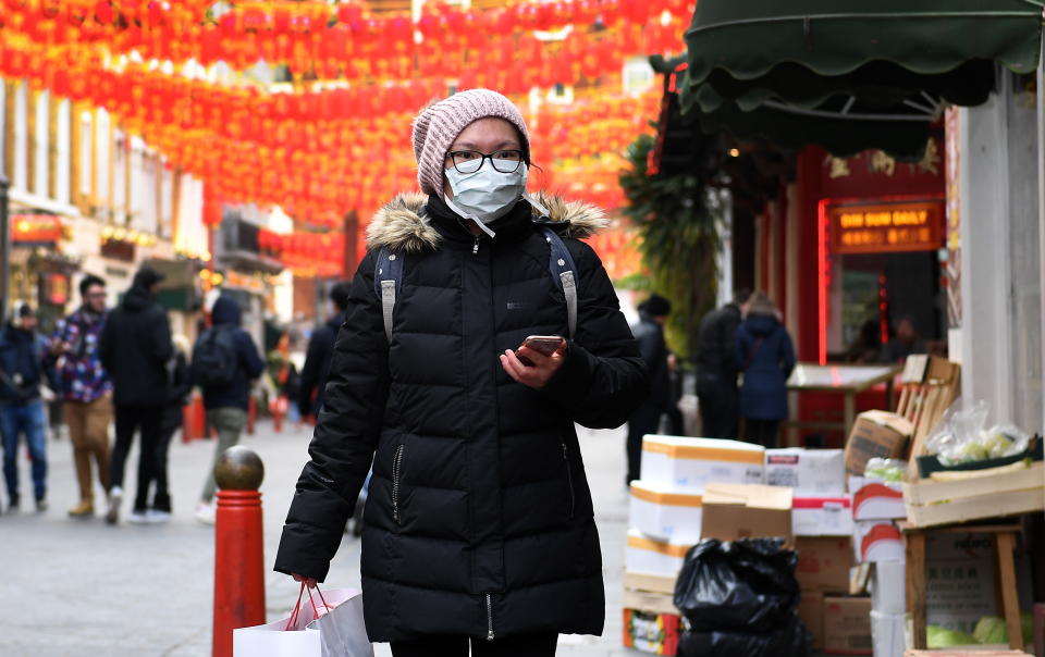 A woman covers her face while visiting a Chinatown in London during the coronavirus outbreak. Source: AAP