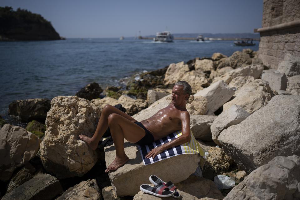 FILE - A man sunbathes in high temperatures in Marseille, southern France, Aug. 19, 2023. The European climate agency calculates that November, for the sixth month in a row, the globe set a new monthly record for heat, adding the hottest autumn to the broken records of record-breaking heat this year. (AP Photo/Daniel Cole, File)