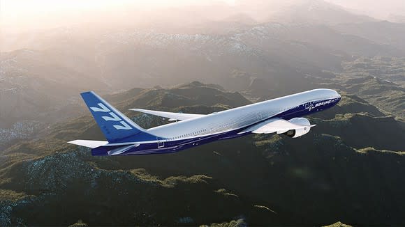 A 777-300ER flying over mountainous terrain