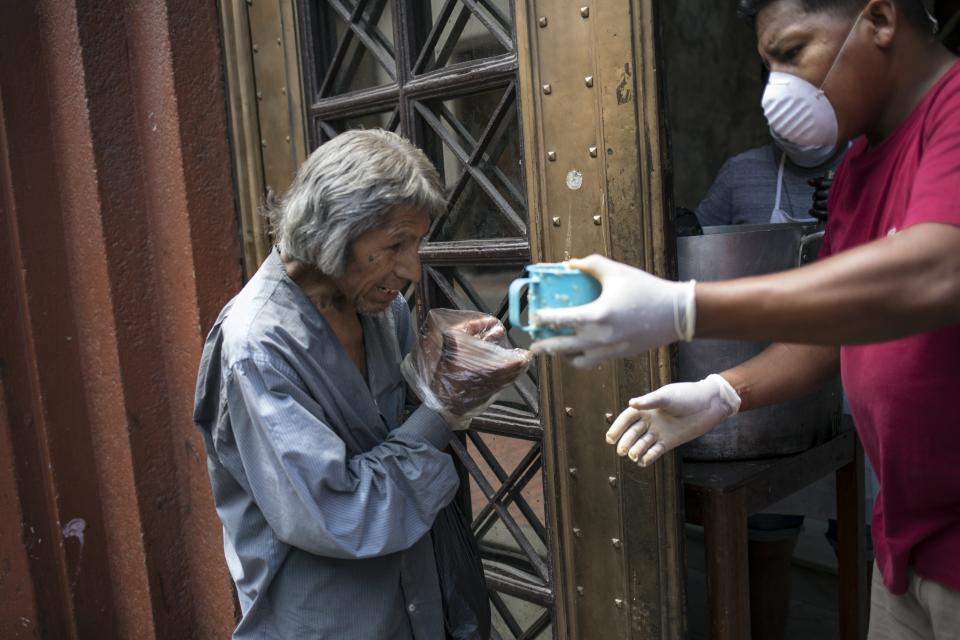 Un hombre utiliza bolsas de plástico como guantes desechables improvisados para tomar una taza de sopa gratis, en Lima, Perú, el jueves 26 de marzo de 2020, durante un decreto de emergencia que recluye a la gente en sus hogares para frenar los contagios del nuevo coronavirus. Al menos 14 millones de personas podrían pasar hambre en América Latina al agravarse la pandemia del coronavirus, que recluye a la gente en su casa, destruye puestos de trabajo y lastra a la economía, según advirtió el Programa Mundial de Alimentos de Naciones Unidas. (AP Foto/Rodrigo Abd)