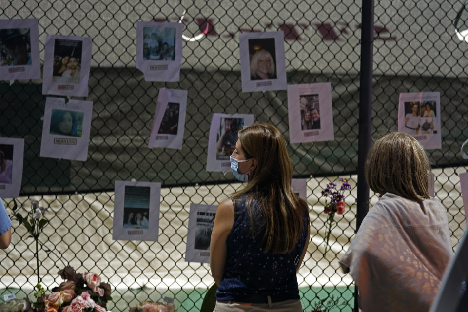 Angelica Pulido looks at a makeshift memorial with photos of some of the missing people near the site of an oceanfront condo building that partially collapsed in Surfside, Fla., Friday, June 25, 2021. (AP Photo/Gerald Herbert)