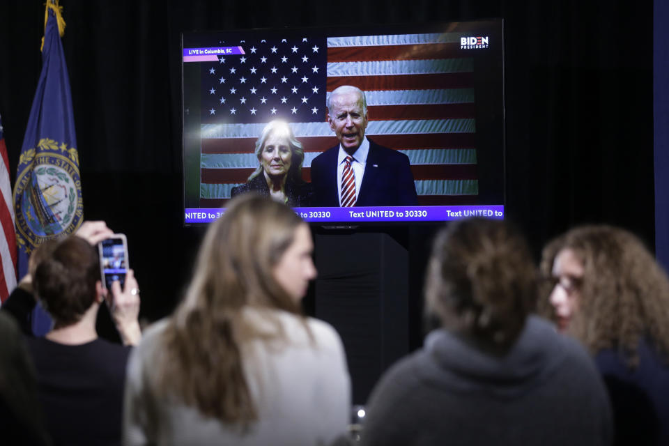 Supporters of Democratic presidential candidate former Vice President Joe Biden watch as Biden, behind right, and his wife Jill Biden, behind left, appear in a video transmission during a primary election night rally, Tuesday, Feb. 11, 2020, in Nashua, N.H. (AP Photo/Steven Senne)