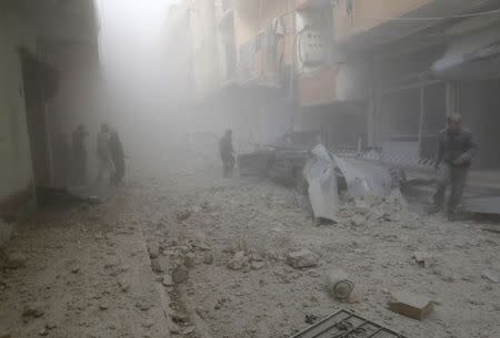 People walk on rubble as they inspect a site hit by what activists said were airstrikes by forces loyal to Syria's President Bashar al-Assad in Raqqa, eastern Syria, which is controlled by the Islamic State November 27, 2014. REUTERS/Nour Fourat