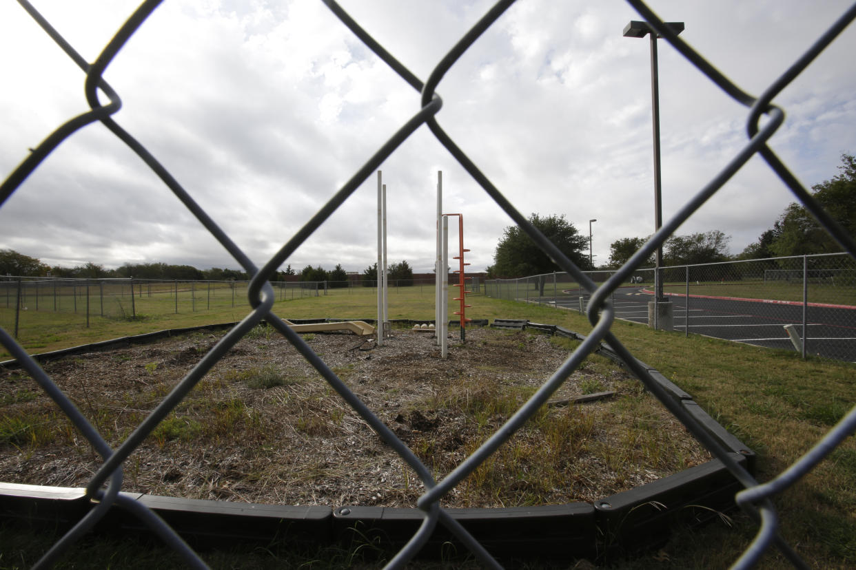 A fence surrounds an abandoned playground near a natural gas well site in Arlington, Texas, on Sunday, Oct. 24, 2021. The playground at the Cornerstone Baptist Church and school was closed because it is about 400 feet from wells at the site, which is now operated by TEP Barnett, a subsidiary of French energy giant Total Energies. Church leaders signed a deal with the original well site owners to use the land for drilling and say they have received a "substantial" amount of royalties. A new playground was built about 200 feet to the north of this one, putting it just beyond the 600 feet minimum required by the city of Arlington. (AP Photo/Martha Irvine)