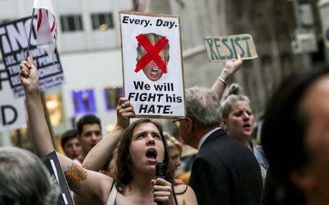 A demonstrator chants and holds a sign outside Trump Tower  - Credit: Bloomberg