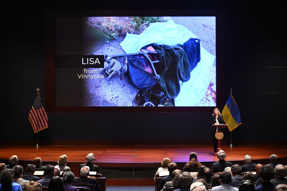 An audience listens to Olena Zelenska, as a screen shows the stroller of Lisa, a 4-year-old killed by a Russian missile attack.