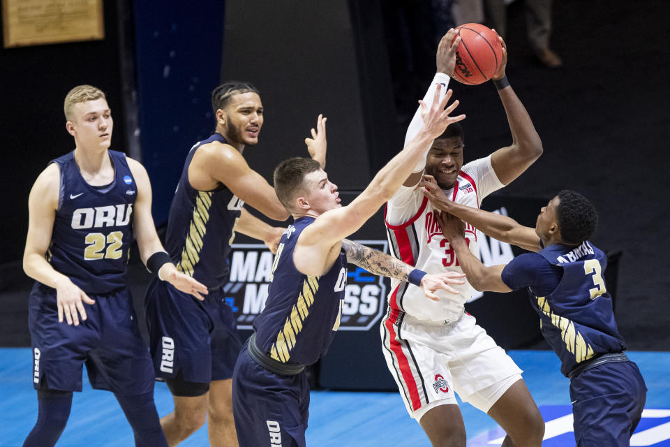 Ohio State's E.J. Liddell, second from right, gets pressure from Oral Roberts' Francis Lacis (22), Kevin Obanor, second from left, Carlos Jürgens, center, and Max Abmas (3) during the second half of a first-round game in the NCAA men's college basketball tournament, Friday, March 19, 2021, at Mackey Arena in West Lafayette, Ind. Oral Roberts won in overtime. (AP Photo/Robert Franklin)