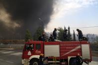 Firefighters arrive at a burning factory in Kapandriti village, about 38 kilometres (23 miles) north of Athens, Greece, Friday, Aug. 6, 2021. Thousands of people fled wildfires burning out of control in Greece and Turkey on Friday, as a protracted heat wave turned forests into tinderboxes and flames threatened populated areas, electricity installations and historic sites. (AP Photo/Thanassis Stavrakis)