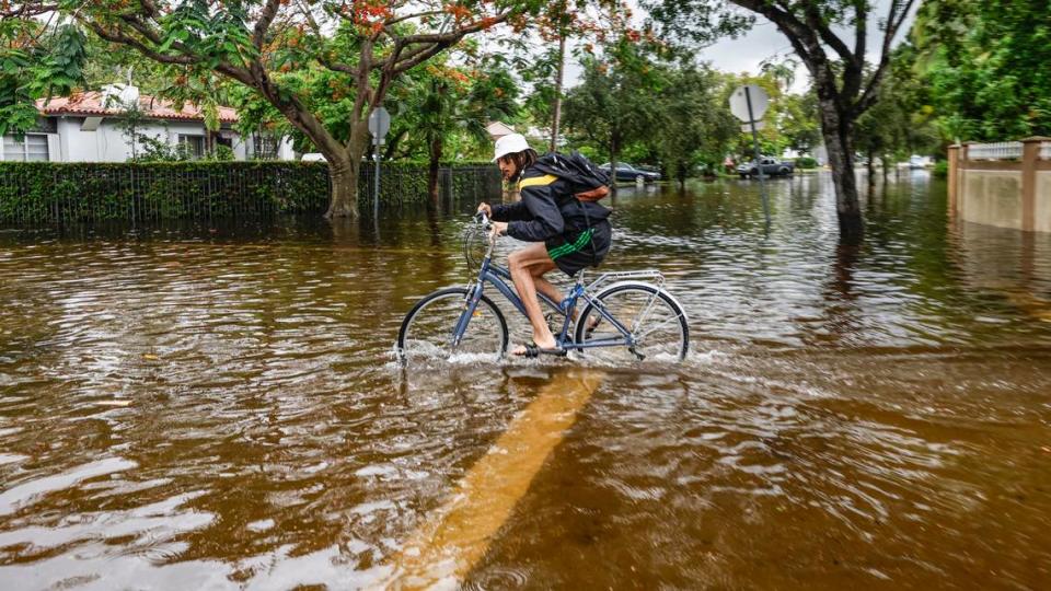 Carlos Armstrong, de 25 años, yendo en bicicleta a su casa dañada por las aguas de inundación cerca de NE 123 street y 11 Court en North Miami el jueves 13 de junio de 2024.