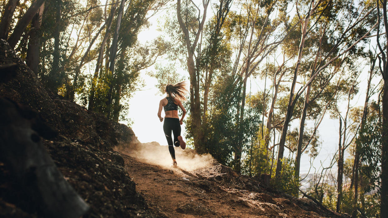 Rear view of woman trail running on a mountain path.