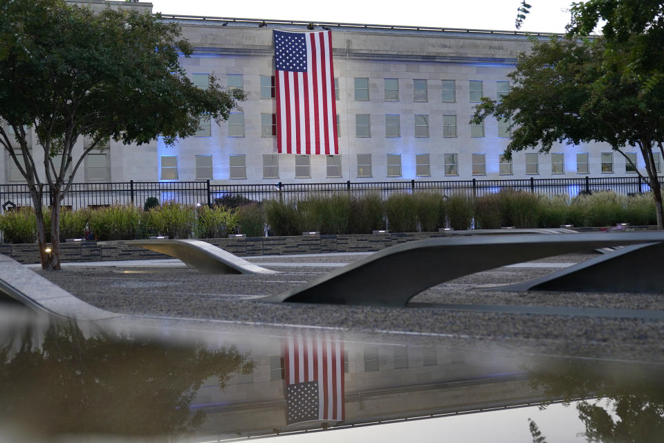 An American flag is unfurled at the Pentagon in Washington, Saturday, Sept. 11, 2021, at sunrise on the morning of the 20th anniversary of the terrorist attacks. The American flag is draped over the site of impact at the Pentagon. In the foreground, the National 9/11 Pentagon Memorial, opened in 2008 adjacent to the site, commemorates the lives lost at the Pentagon and onboard American Airlines Flight 77. (AP Photo/Alex Brandon)