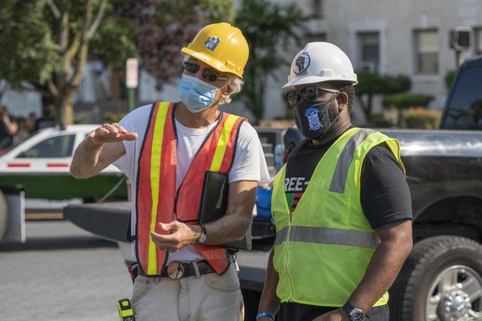 In this photo provided by Sanjay Suchak, Richmond sculptor Paul DiPasquale, left, talks with Devon Henry during the removal of the J.E.B. Stuart statue on Monument Avenue on Tuesday July 7, 2020 in Richmond, Va. Sanjay Suchak via AP)