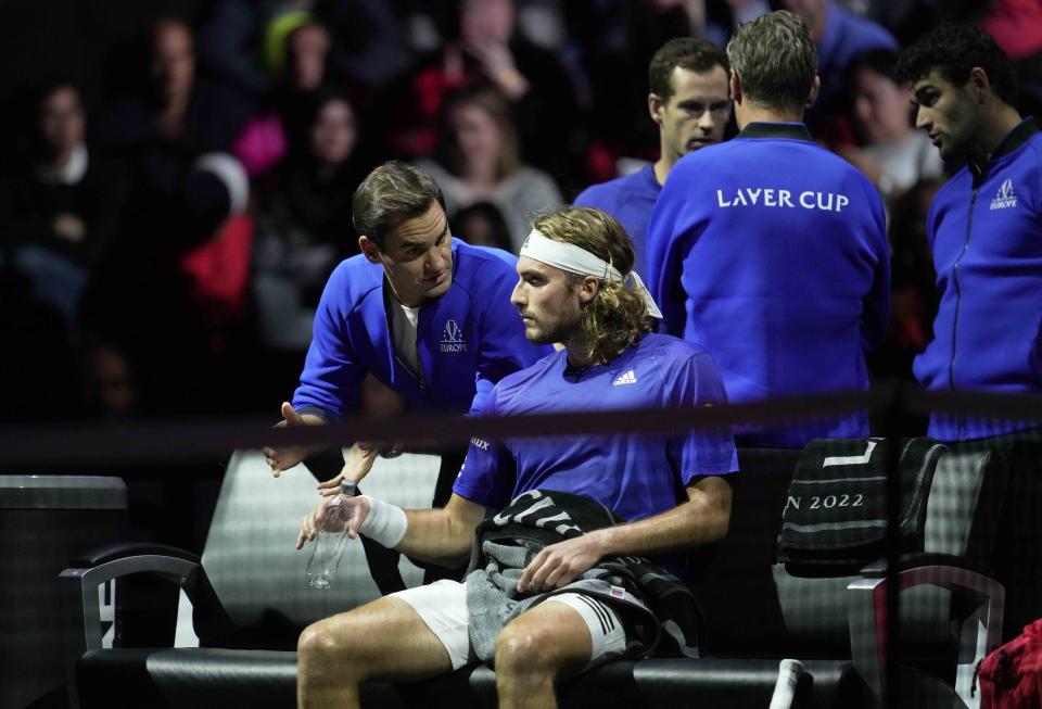 Team Europe's Roger Federer speaks with teammate Stefanos Tsitsipas during the latter's singles tennis match against Team World's Frances Tiafoe on the third day of the Laver Cup tennis tournament at the O2 arena in London, Sunday, Sept. 25, 2022. (AP Photo/Kin Cheung)