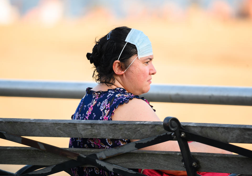 NEW YORK, NEW YORK - JULY 05: A person wears a face mask on her forehead at Brighton Beach in Coney Island as New York City moves into Phase 2 of re-opening following restrictions imposed to curb the coronavirus pandemic on July 5, 2020. Phase 2 permits the reopening of offices, in-store retail, outdoor dining, barbers and beauty parlors and numerous other businesses. Phase 2 is the second of four phased stages designated by the state. (Photo by Noam Galai/Getty Images)