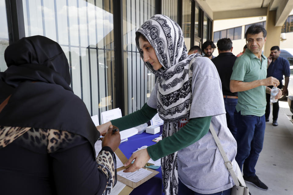 Niloufar Hafizi, center, a volunteer with Emgage Texas, helps Maimouna Cissoko, left, with voter registration forms outside the Masjid Al-Qur'an mosque after prayers Wednesday, July 28, 2023, in Houston. (AP Photo/Michael Wyke)