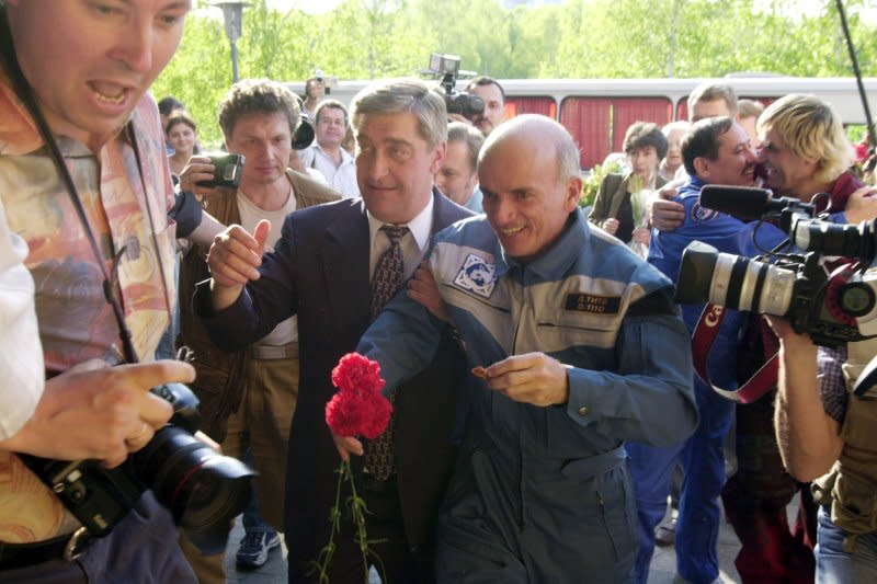 Supported by a Russian Space Agency officer, American multimillionaire Dennis Tito (R) walks during a ceremony in Star City, outside Moscow, on May 6, 2001. On April 28, 2001, Tito became the first tourist in space. File Photo by Michael Levkin/UPI
