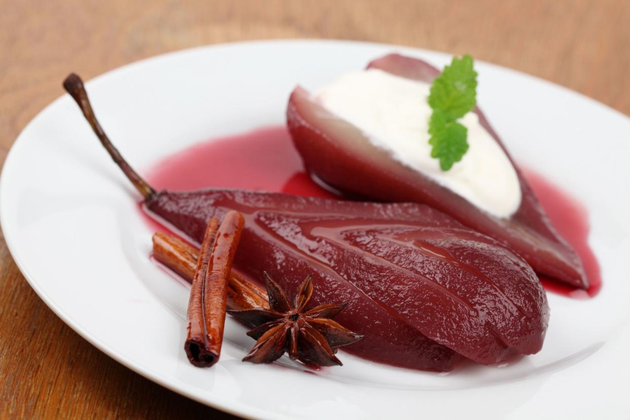 poached pears on plate with cream, star anise and cinnamon